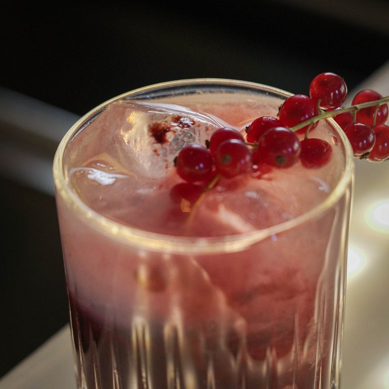 Caipi Berry im Tumbler, garniert mit einer Rispe roter Johannisbeeren