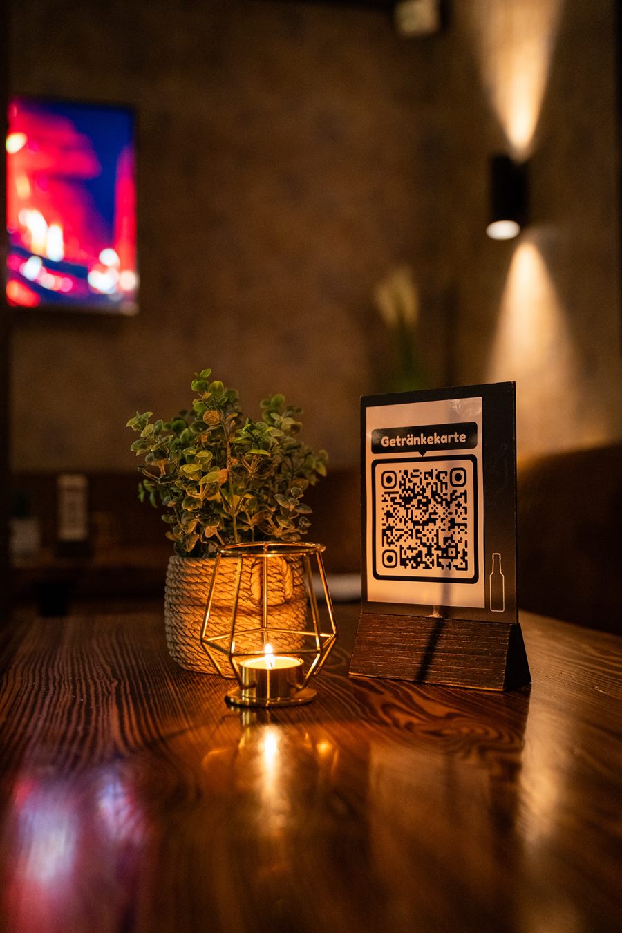Kerzenlicht, Grünpflanze und die Getränkekarte als QR-Code auf dem Tisch